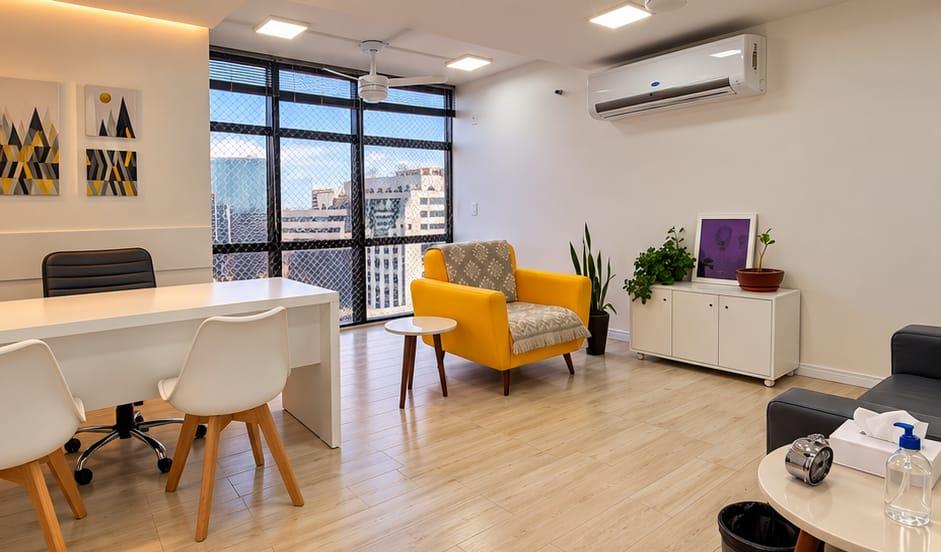 Sala de atendimento ampla com mesa, poltrona amarela e vista para a cidade